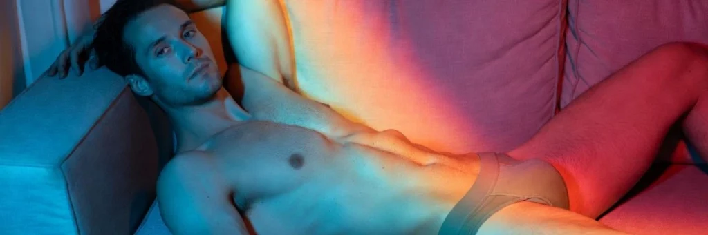 Relaxed man lying on a couch in underwear with soft lighting